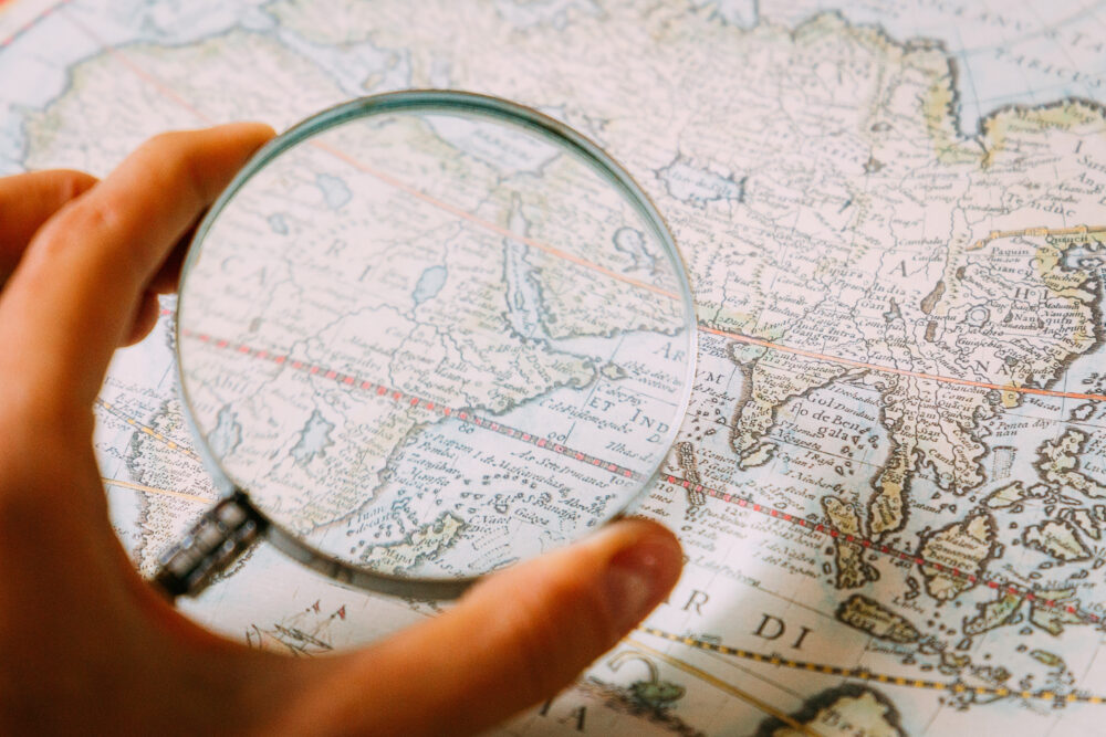 Magnifying Glass in Woman’s Hand and Ancient Old Map