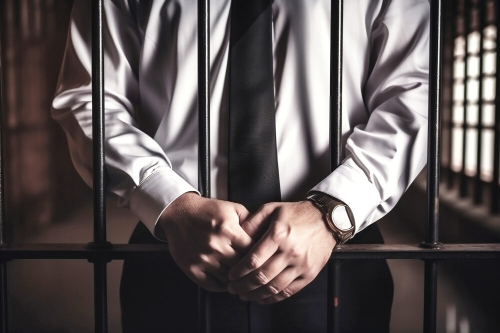 A politician or businessman in a business suit behind prison bars. Corruption in government and business. Punishment for a crime.